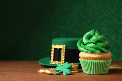 Photo of Composition with delicious decorated cupcake on wooden table. St. Patrick's Day celebration