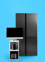 Photo of Modern refrigerator and other household appliances on blue background