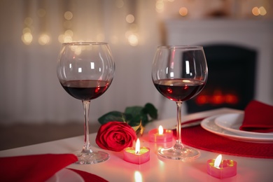 Photo of Romantic table setting with wine, rose and candles for Valentine's day dinner indoors