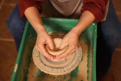 Photo of Woman crafting with clay on potter's wheel, closeup