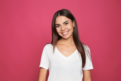 Portrait of young woman laughing on color background