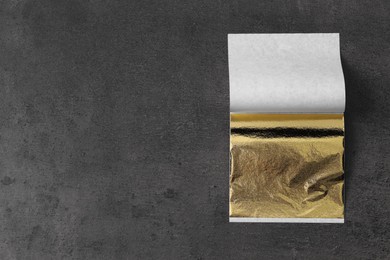 Photo of Edible gold leaf sheet on textured table, top view. Space for text