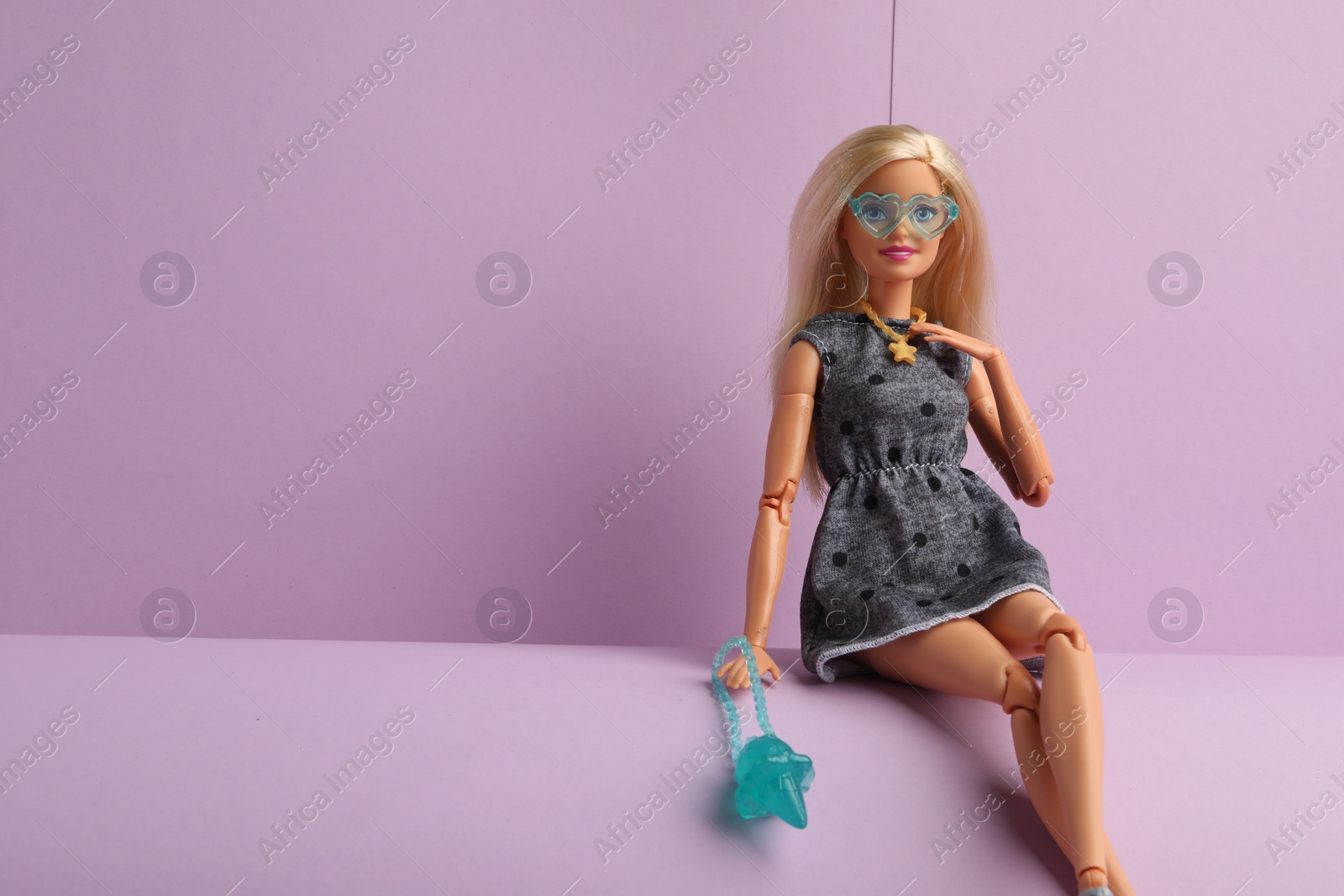 Photo of Mykolaiv, Ukraine - September 4, 2023: Beautiful Barbie doll with bag sitting on lilac background, space for text