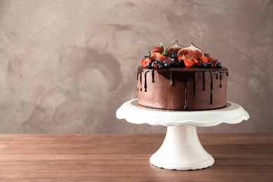 Photo of Fresh delicious homemade chocolate cake with berries on table against color background. Space for text