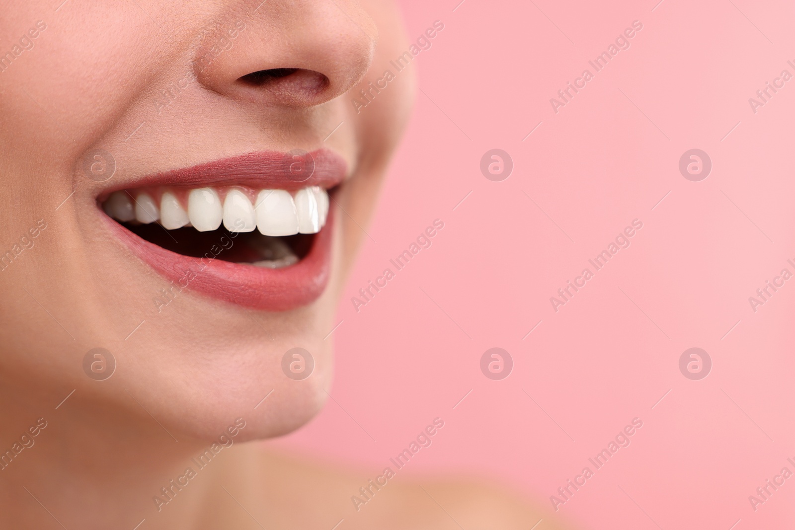 Photo of Woman with beautiful lips smiling on pink background, closeup. Space for text