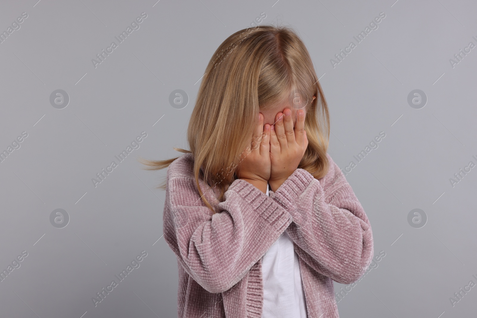 Photo of Resentful girl covering face with hands on grey background