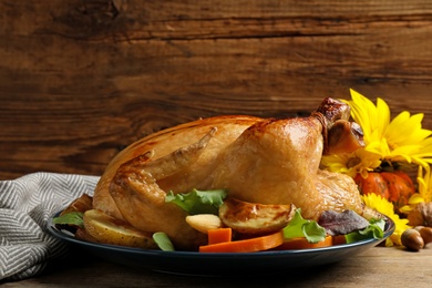 Photo of Traditional cooked turkey and autumn decor on wooden table. Thanksgiving day celebration