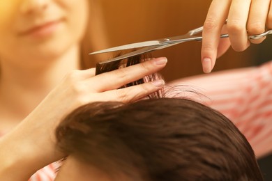 Image of Barber making stylish haircut with professional scissors in beauty salon, closeup