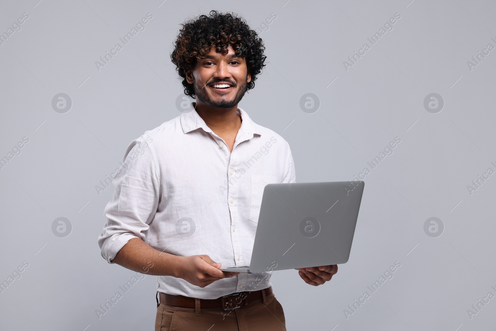 Photo of Smiling man with laptop on light grey background, space for text