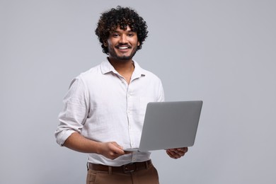 Photo of Smiling man with laptop on light grey background, space for text