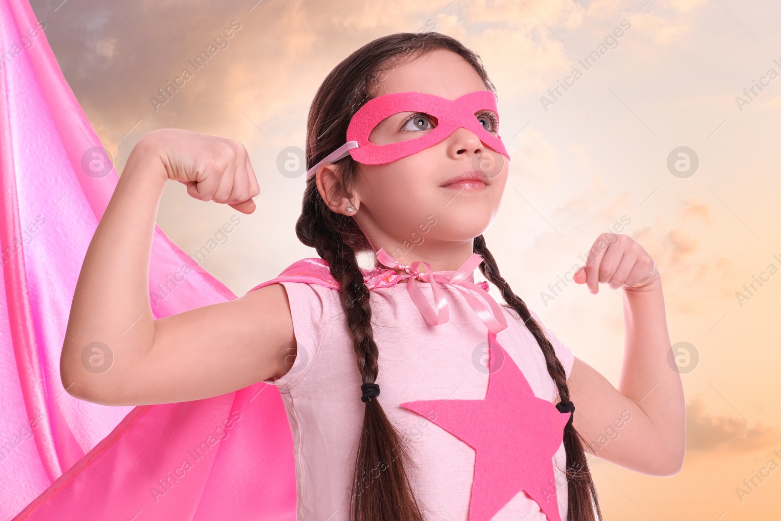 Image of Cute little girl in superhero costume against cloudy sky