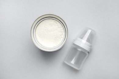 Photo of Can of powdered infant formula with feeding bottle on light background, flat lay. Baby milk