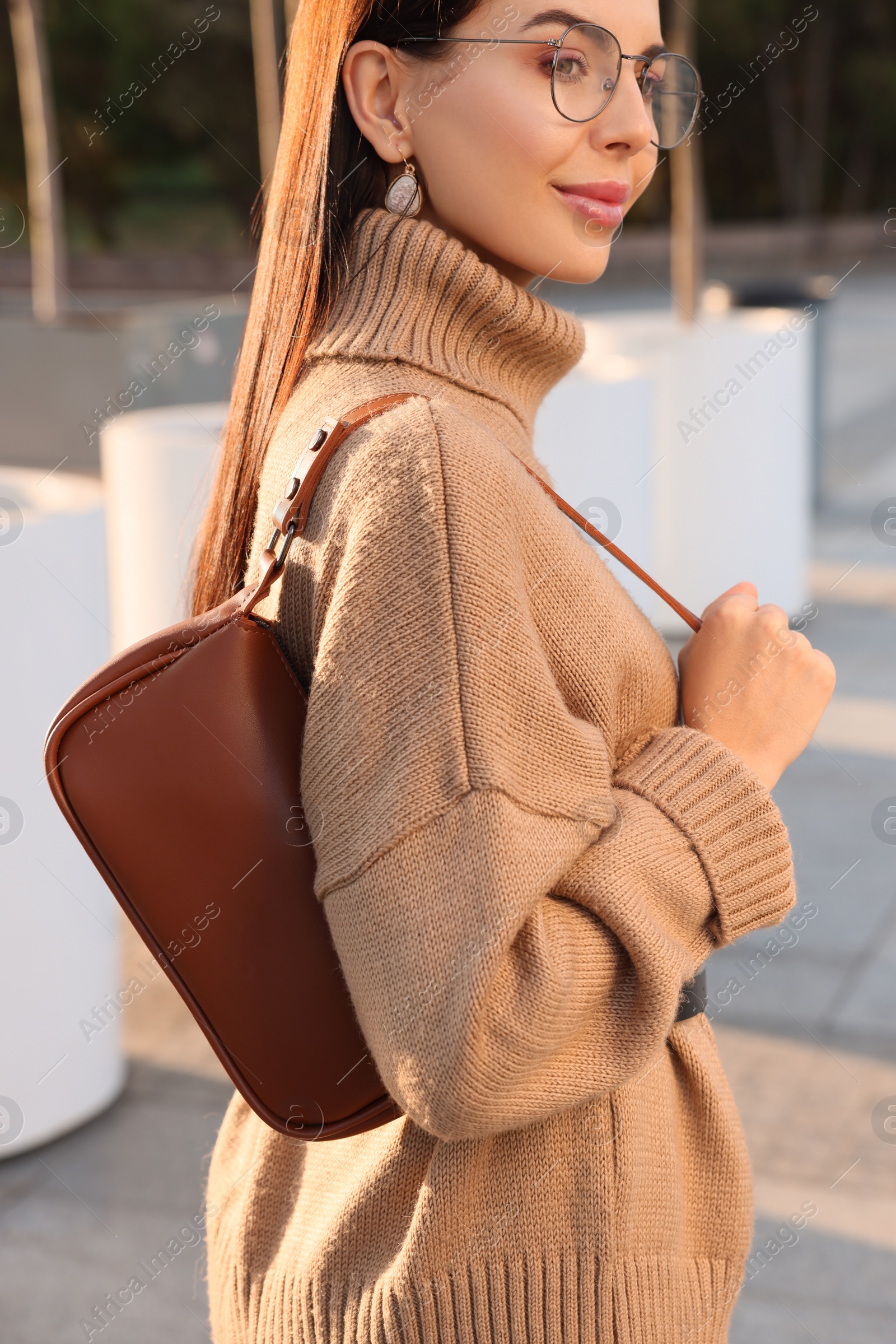 Photo of Fashionable young woman with stylish bag on city street