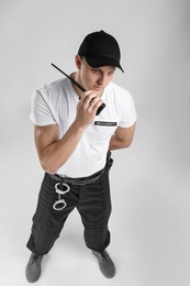 Male security guard using portable radio transmitter on color background