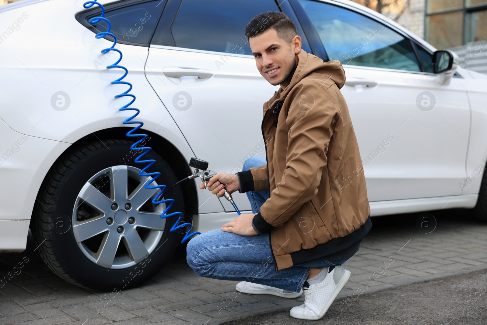 Photo of Handsome man inflating tire at car service