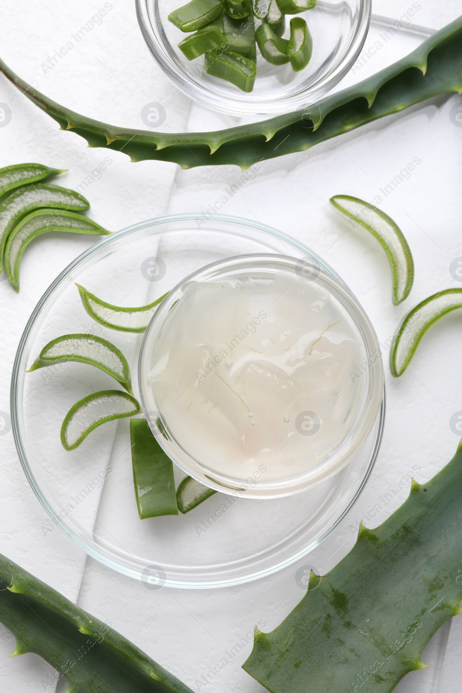 Photo of Aloe vera gel and slices of plant on white background, flat lay