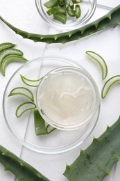 Aloe vera gel and slices of plant on white background, flat lay