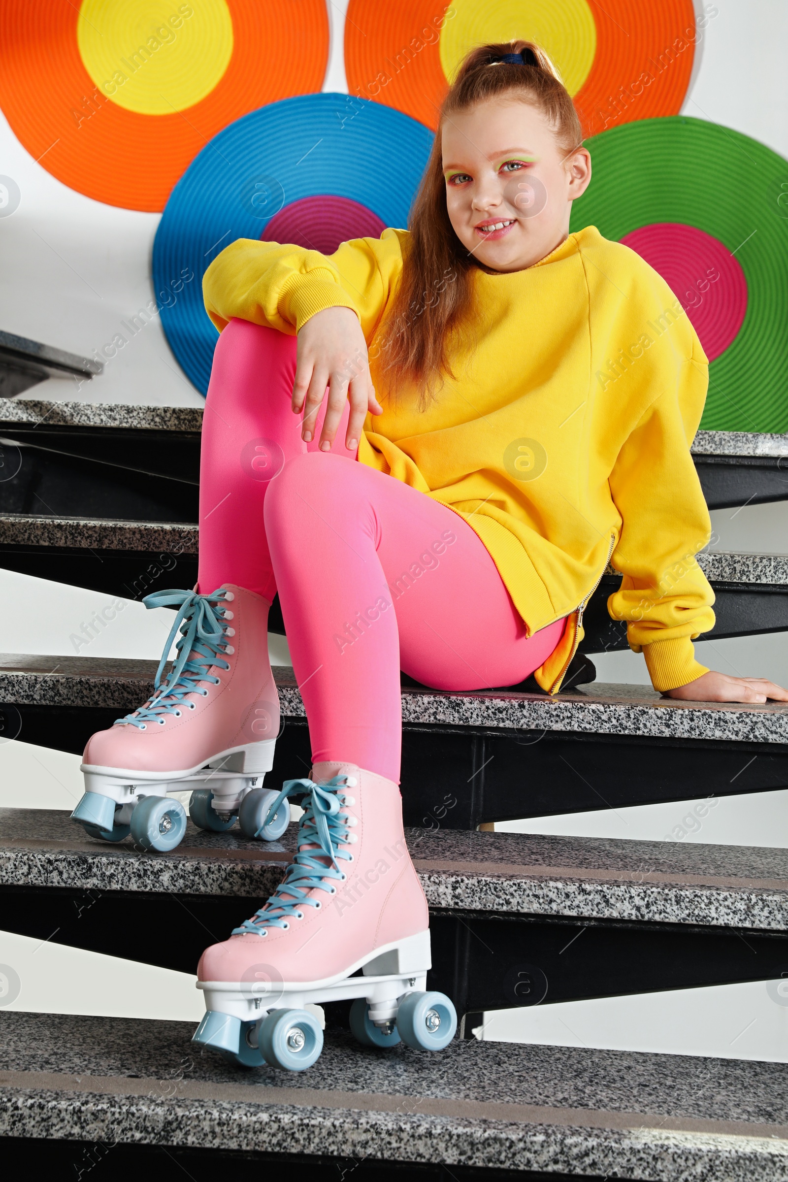 Photo of Cute indie girl with roller skates sitting on stairs indoors