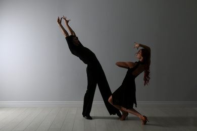 Photo of Beautiful young couple dancing near light wall