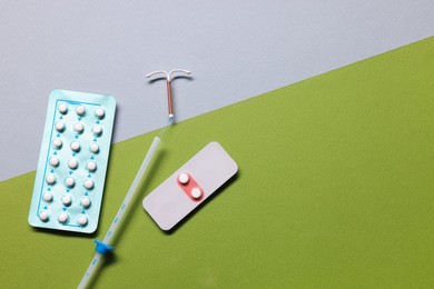 Photo of Birth control pills and intrauterine device on color background, flat lay and space for text. Choosing method of contraception
