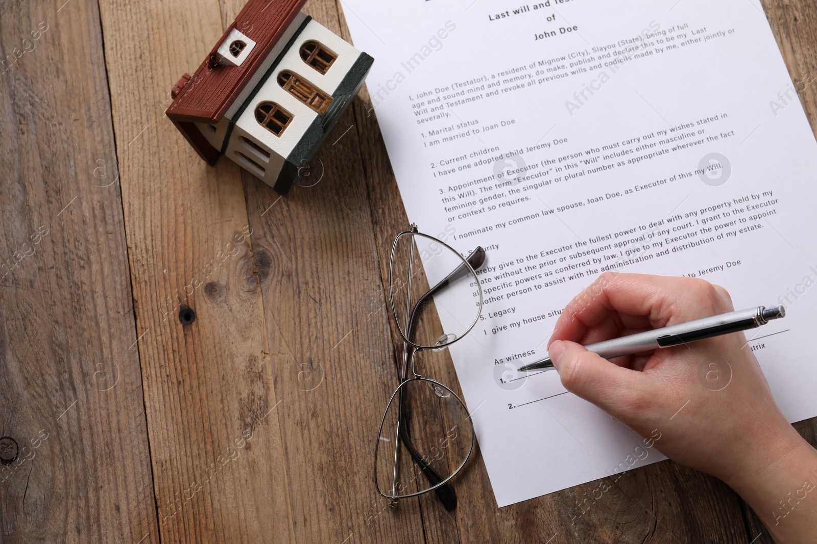 Photo of Woman signing Last Will and Testament at wooden table, top view. Space for text