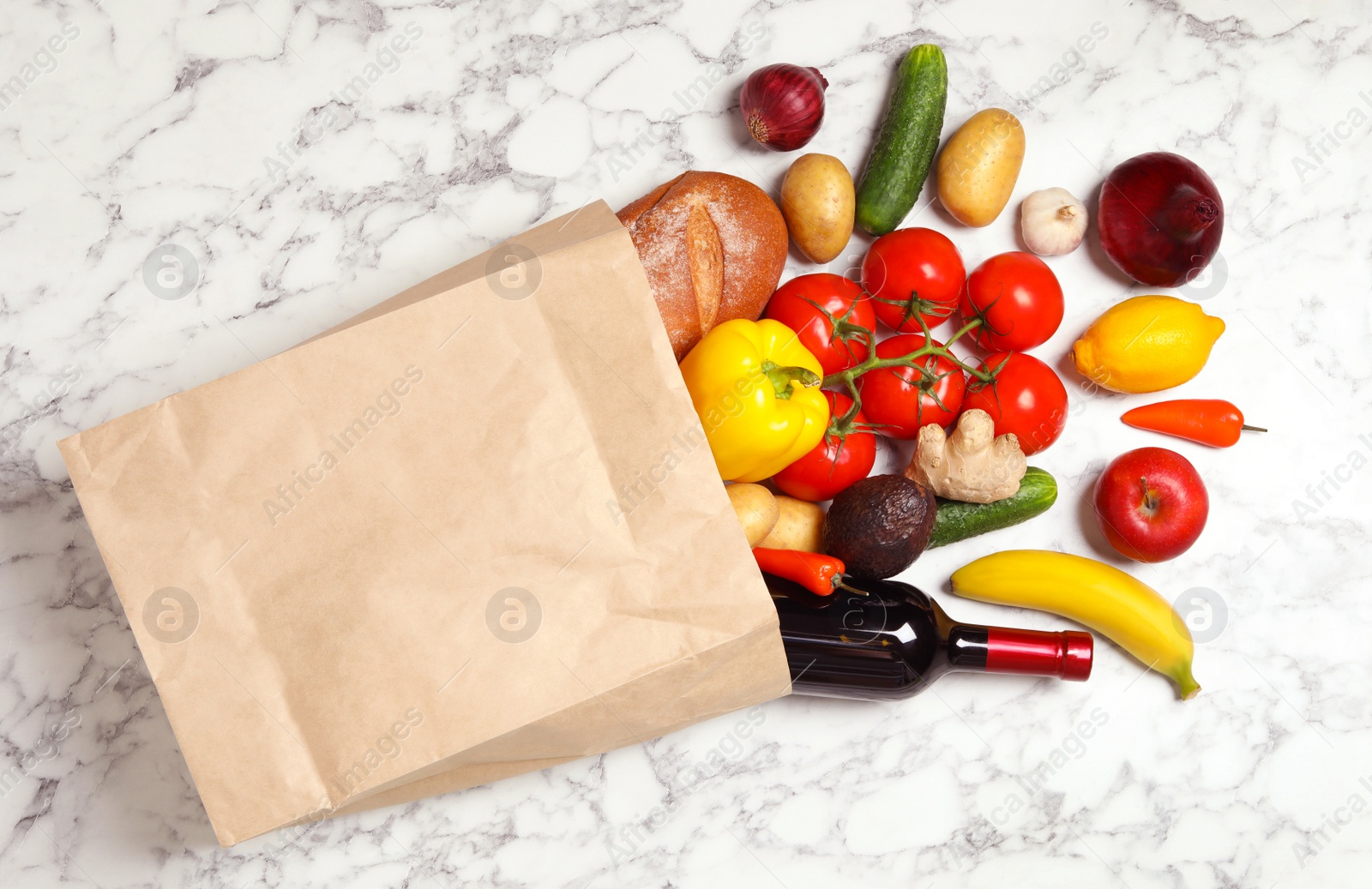 Photo of Shopping paper bag with different groceries on white marble background, flat lay