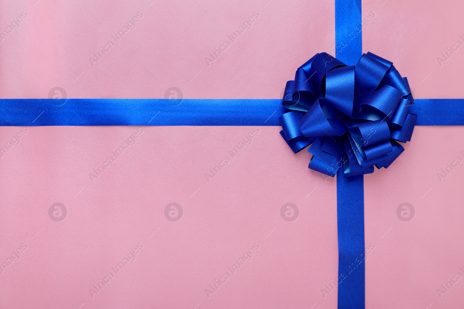 Photo of Blue ribbons with bow on pink background, top view. Space for text