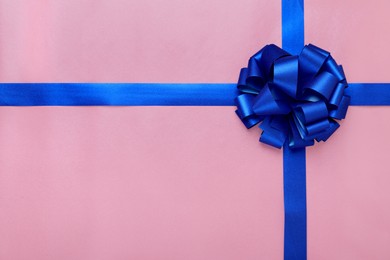 Photo of Blue ribbons with bow on pink background, top view. Space for text