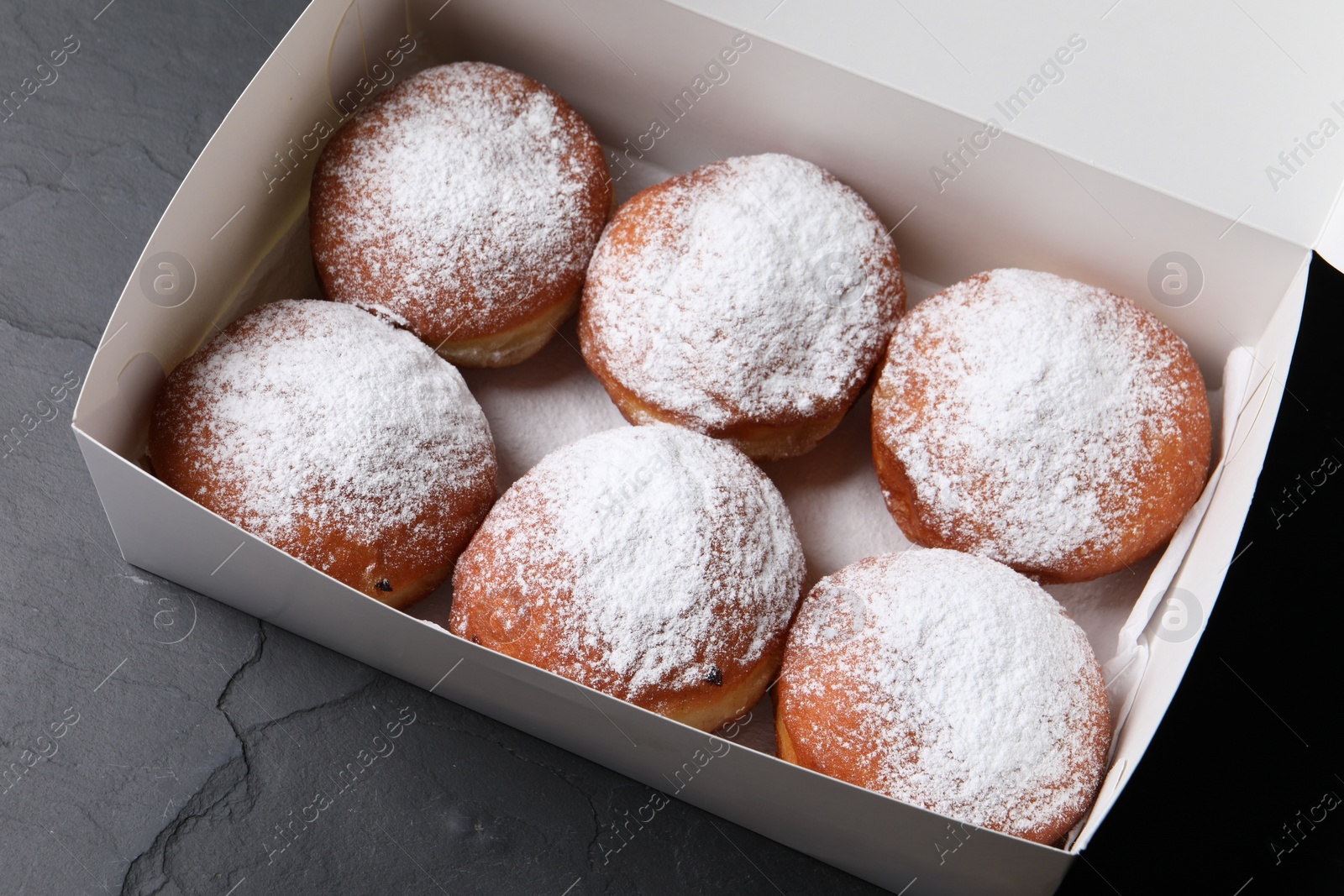 Photo of Delicious sweet buns in box on dark gray table, above view