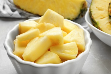 Bowl with fresh sliced pineapple on table, closeup