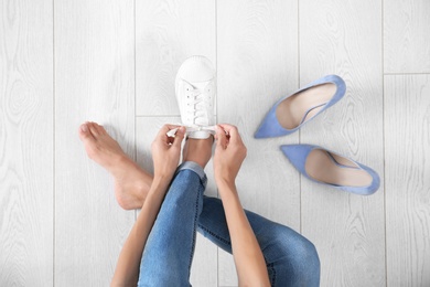 Young woman changing shoes on wooden background, top view