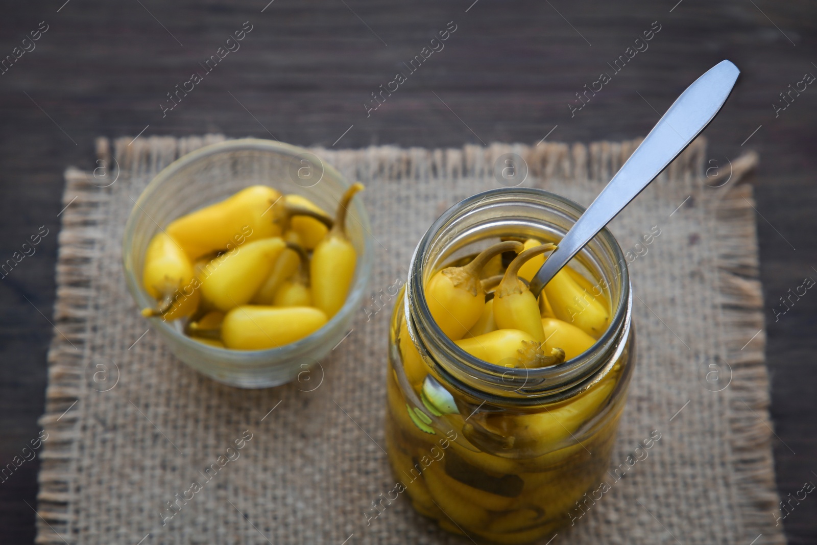 Photo of Pickled yellow jalapeno peppers on wooden table, above view