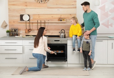 Photo of Happy family baking cookies in oven at home
