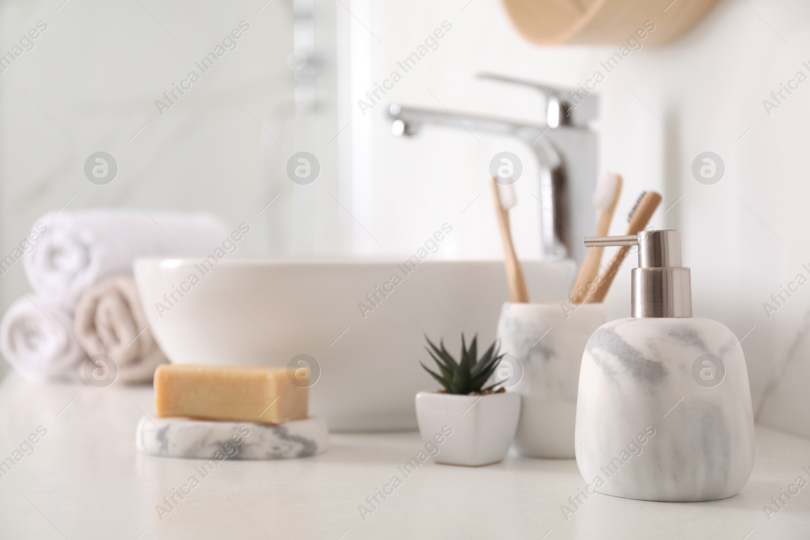 Photo of Holder with toothbrushes, plant and different toiletries near vessel sink in bathroom