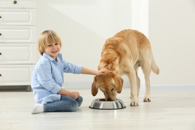 Photo of Cute little child feeding Golden Retriever at home. Adorable pet