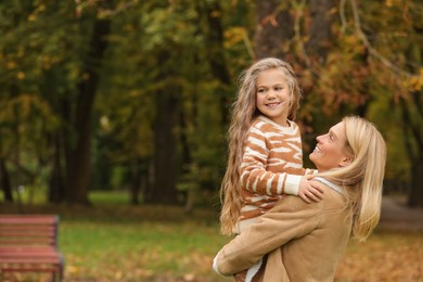 Photo of Happy mother spending time together with her daughter in autumn park, space for text