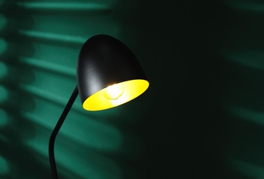 Photo of Stylish black lamp near green wall indoors, space for text