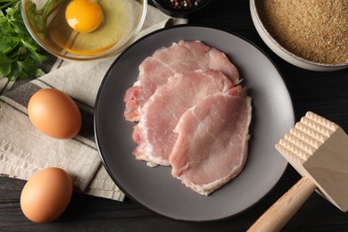 Photo of Cooking schnitzel. Raw pork slices, other ingredients and meat tenderizer on wooden table, flat lay