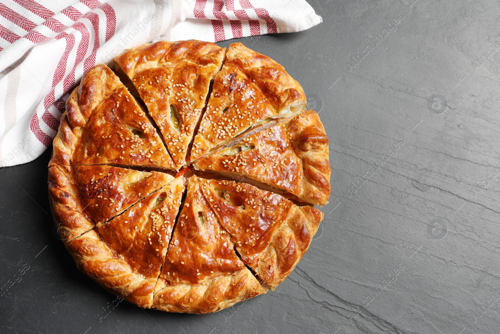 Photo of Cut delicious homemade pie on black table, top view. Space for text