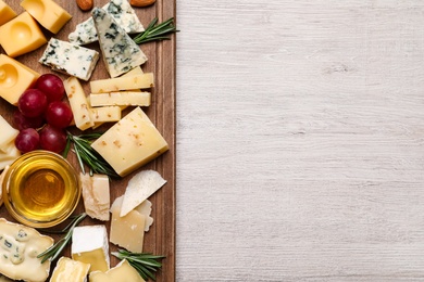 Photo of Cheese plate with honey, grapes and nuts on white table, top view. Space for text