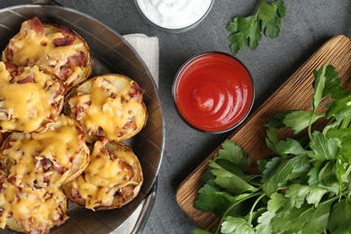 Photo of Flat lay composition with pan of baked potatoes, sauce and parsley on grey background