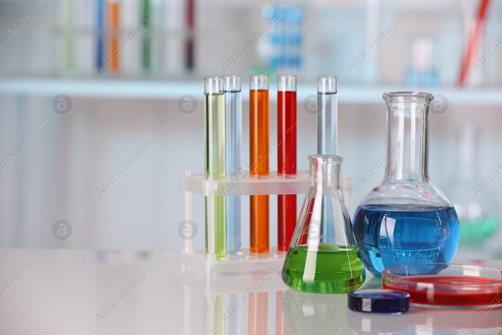 Photo of Laboratory analysis. Different glassware with liquids on white table against blurred background. Space for text