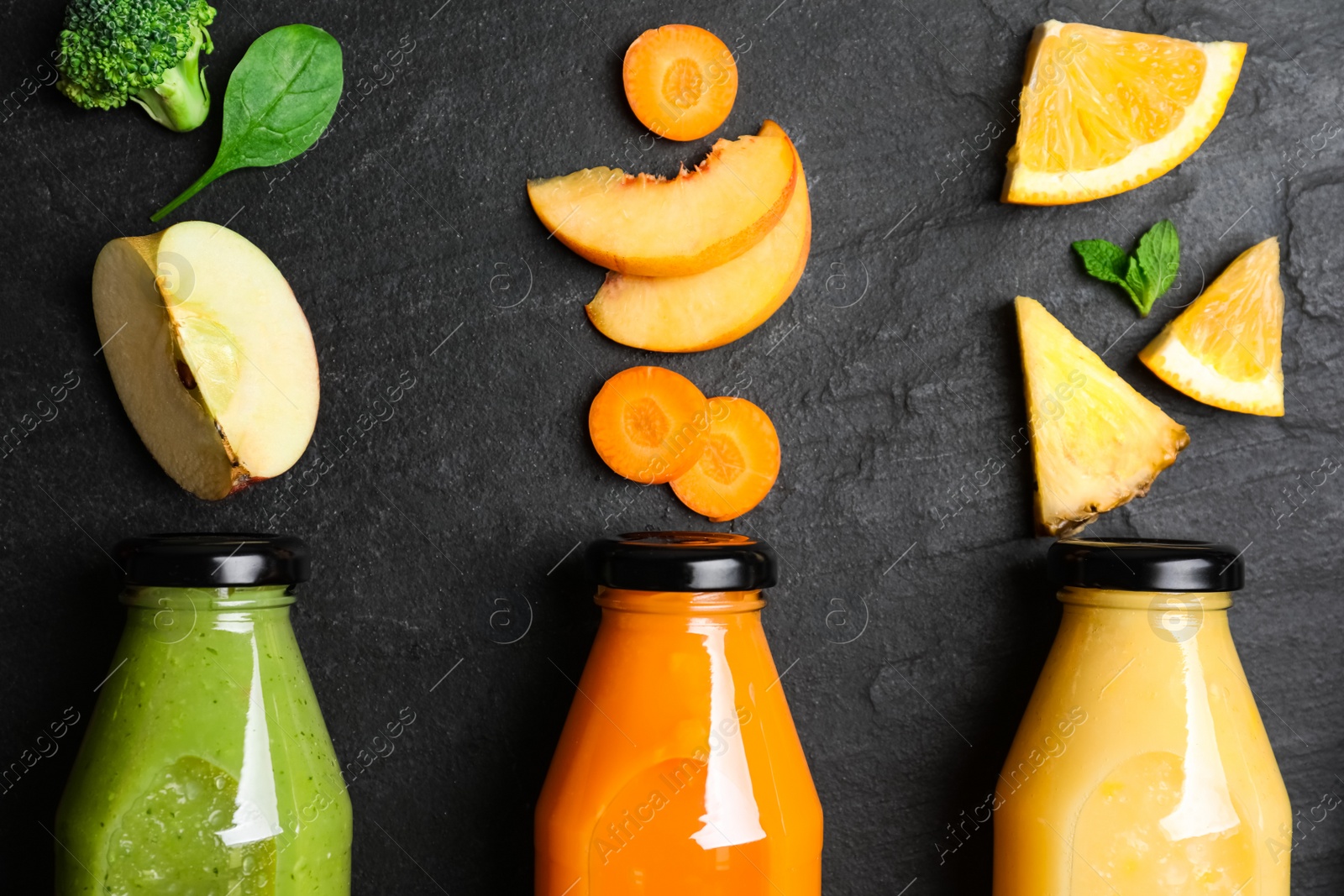 Photo of Flat lay composition with bottles of delicious juices and fresh ingredients on black table