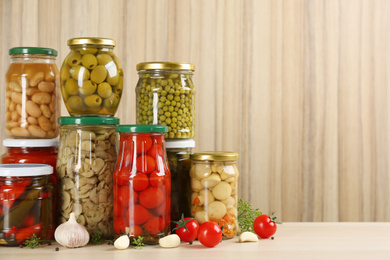 Jars of pickled vegetables on wooden table. Space for text