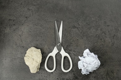 Flat lay composition with rock, paper and scissors on grey stone background