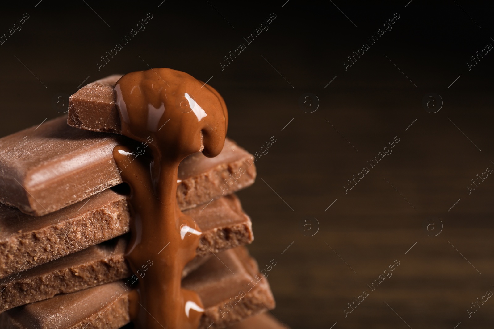 Photo of Pieces of milk chocolate with tasty paste on blurred background, closeup. Space for text