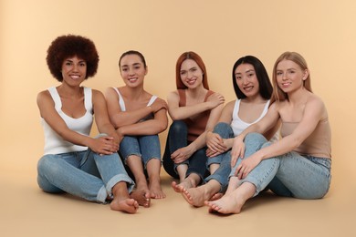 Group of beautiful young women sitting on beige background