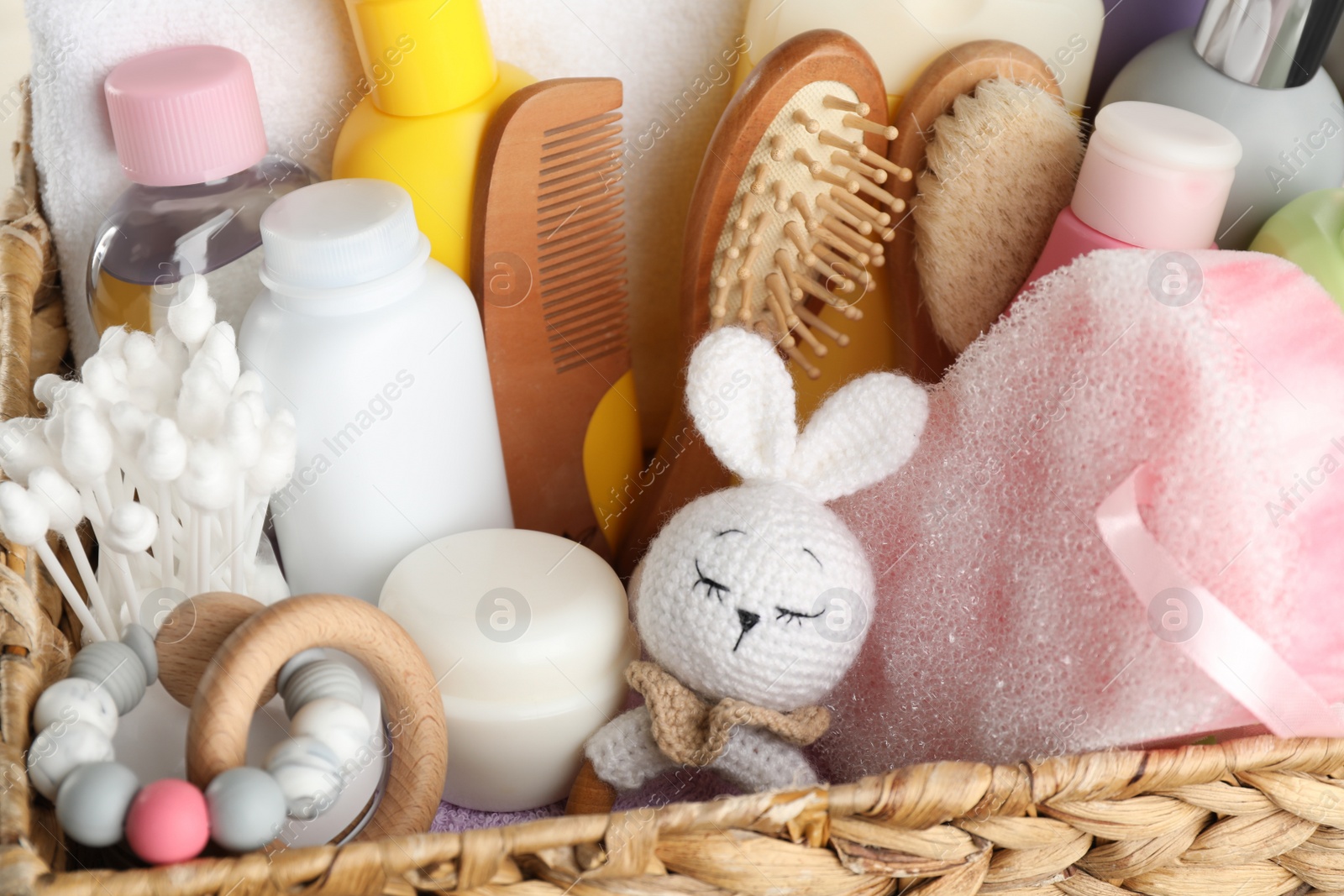 Photo of Wicker basket full of different baby cosmetic products, bathing accessories and toys, closeup