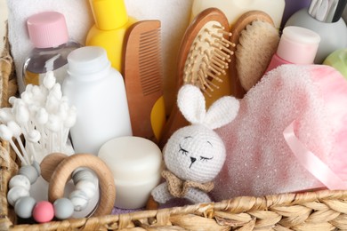 Photo of Wicker basket full of different baby cosmetic products, bathing accessories and toys, closeup