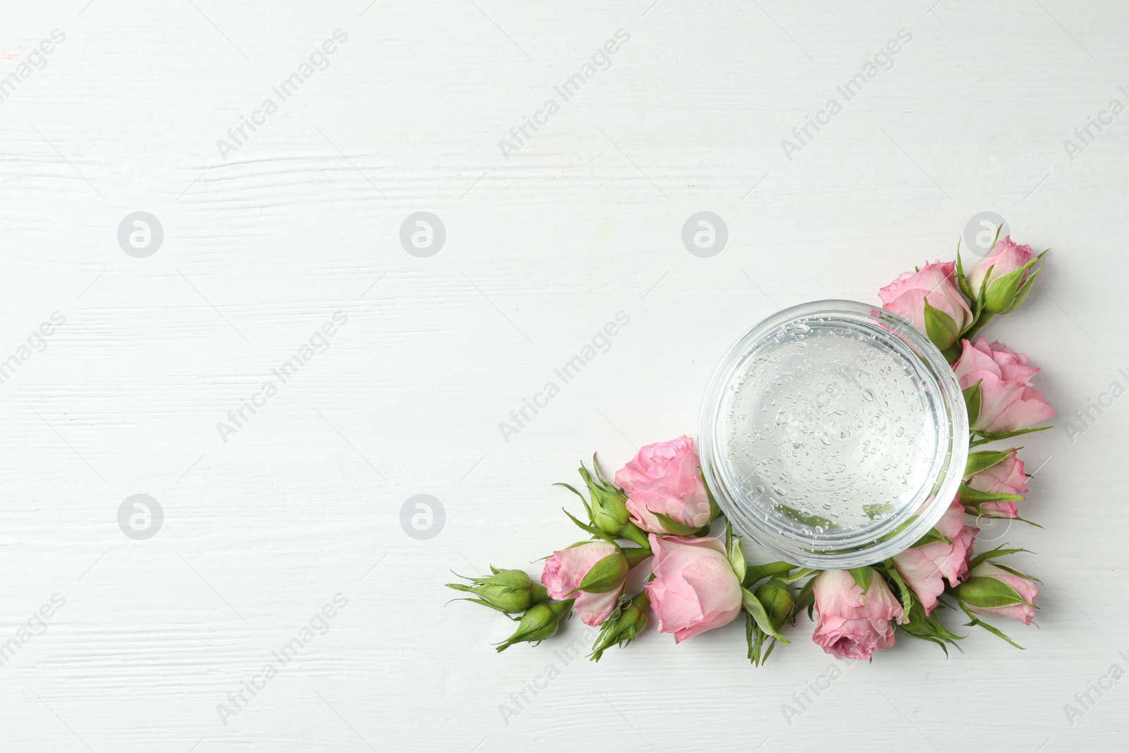 Photo of Flat lay composition with cosmetic gel and beautiful flowers on white wooden table. Space for text